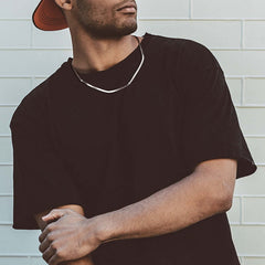 Man wearing a stylish sterling silver snake bone necklace, showcasing minimalist design against a modern background.