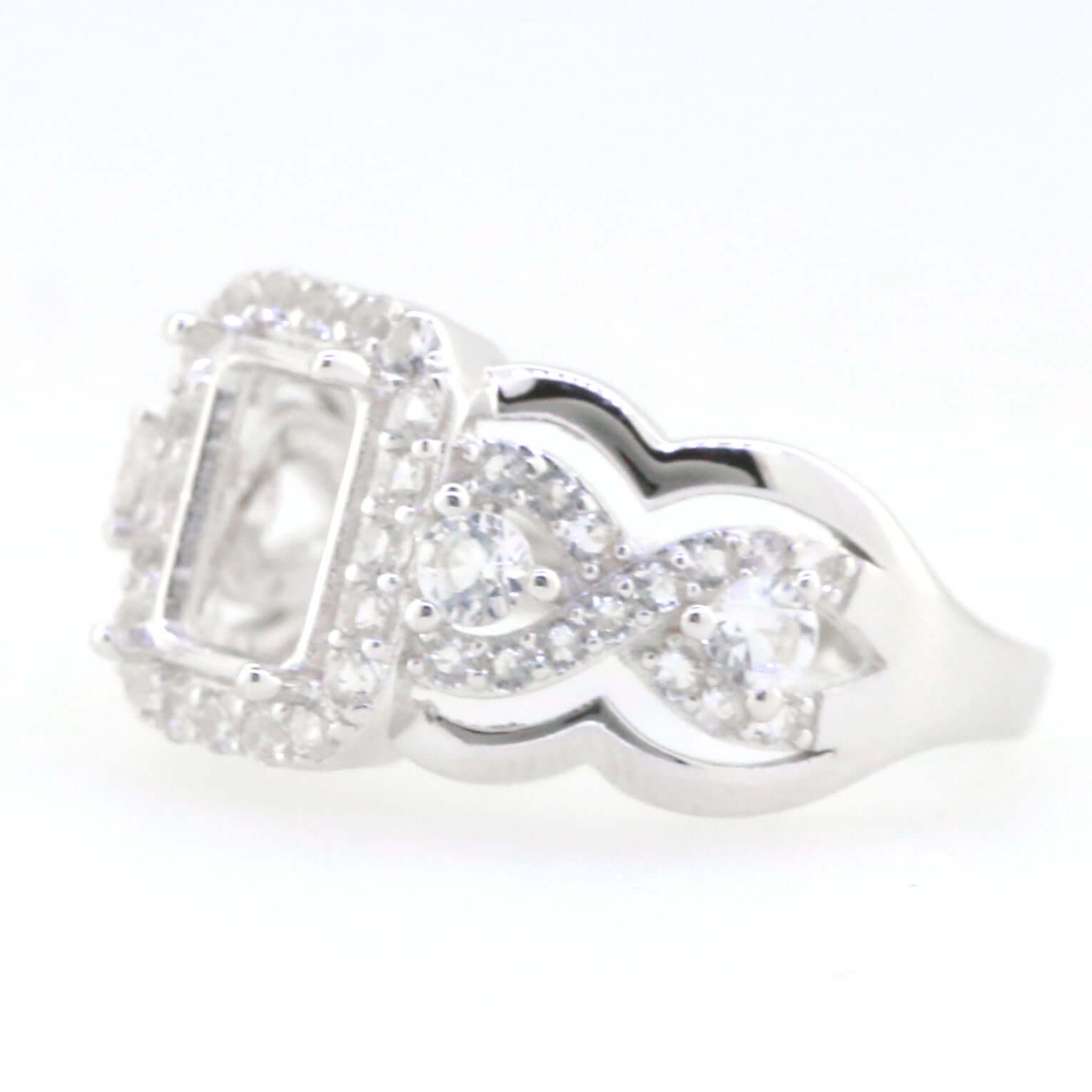 Sterling silver semi mount ring setting with crisscross swirl shank, designed for 8x6mm emerald and white topaz accents.